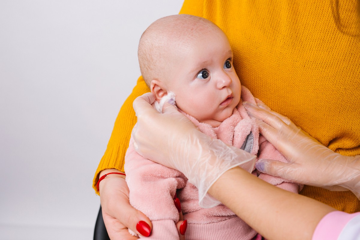 Bebê passando por furo de lóbulo de orelha em ambiente seguro e higienizado
