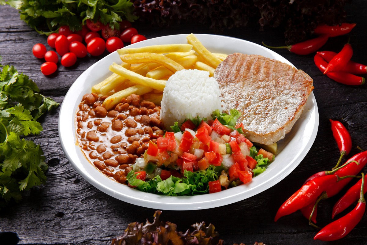 Prato colorido com arroz, feijão, carne e salada, ilustrando como inovar a comida no dia a dia.