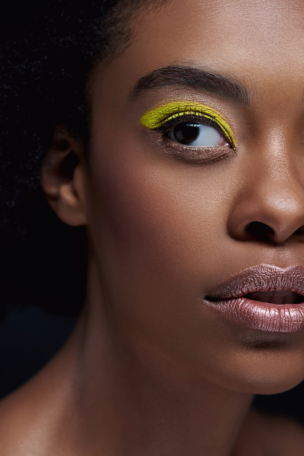 Jovem e linda mulher de pele negra com o rosto maquiado e iluminado