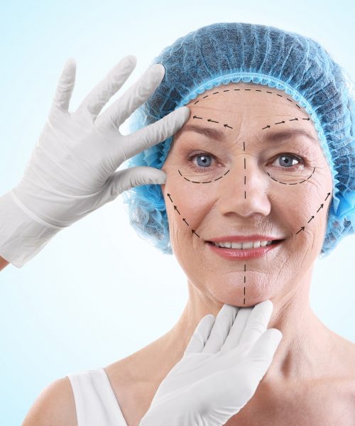 Cirurgião examinando rosto feminino contra fundo azul. Conceito de cirurgia plástica lifting facial